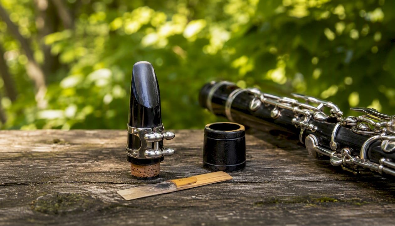 Basset horn mouthpiece and reed on cream surface